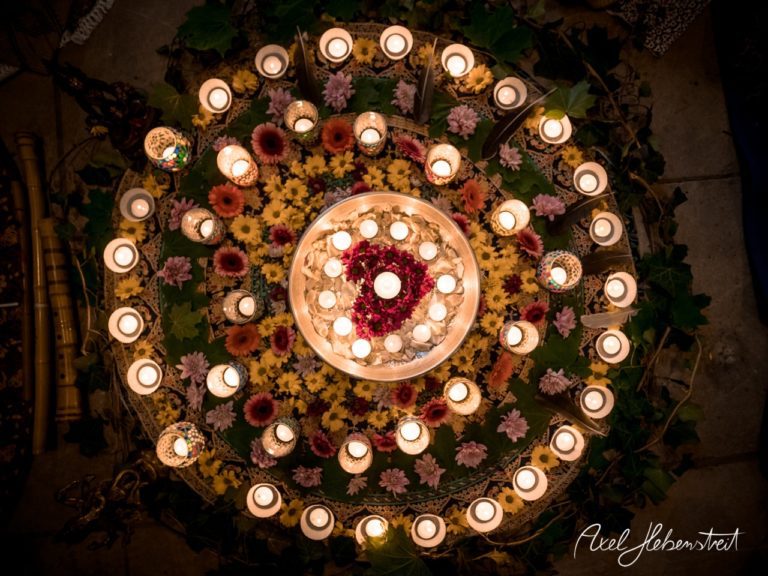 Eine kreisförmige Anordnung aus Kerzen und bunten Blumen schafft eine festliche und friedliche Atmosphäre. – © Axel Hebenstreit
