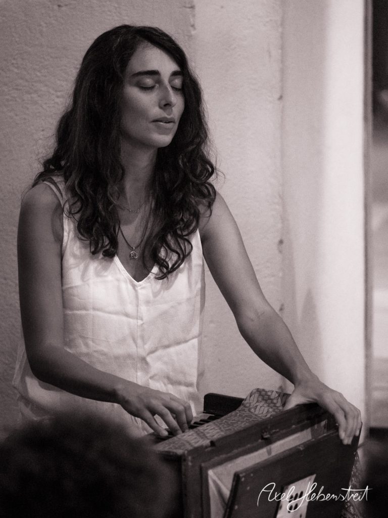 Eine Frau mit langen, offenen Haaren spielt intensiv auf einem Harmonium und strahlt innere Ruhe aus. – © Axel Hebenstreit