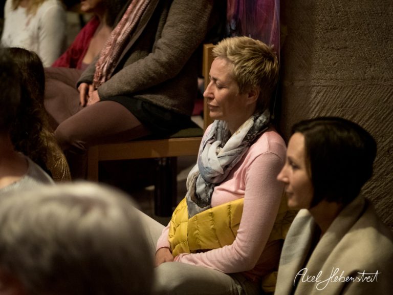 Eine Gruppe von Menschen sitzt in meditativer Stille, umgeben von einer einladenden Atmosphäre. – © Axel Hebenstreit
