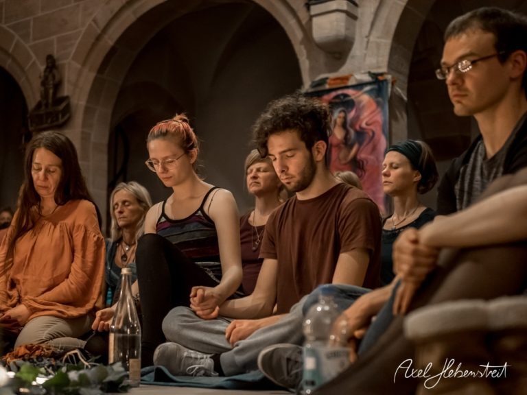 Eine Gruppe von Menschen sitzt in meditativer Stimmung während einer Yogaveranstaltung in einem historischen Raum. – © Axel Hebenstreit