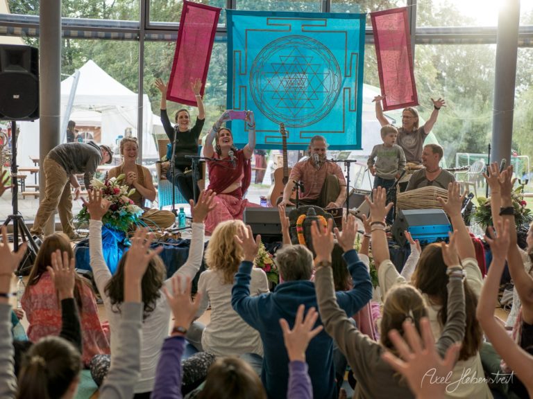 Spirituelles Festival mit Live-Performance auf einer Bühne vor enthusiastischem Publikum mit erhobenen Händen – © Axel Hebenstreit