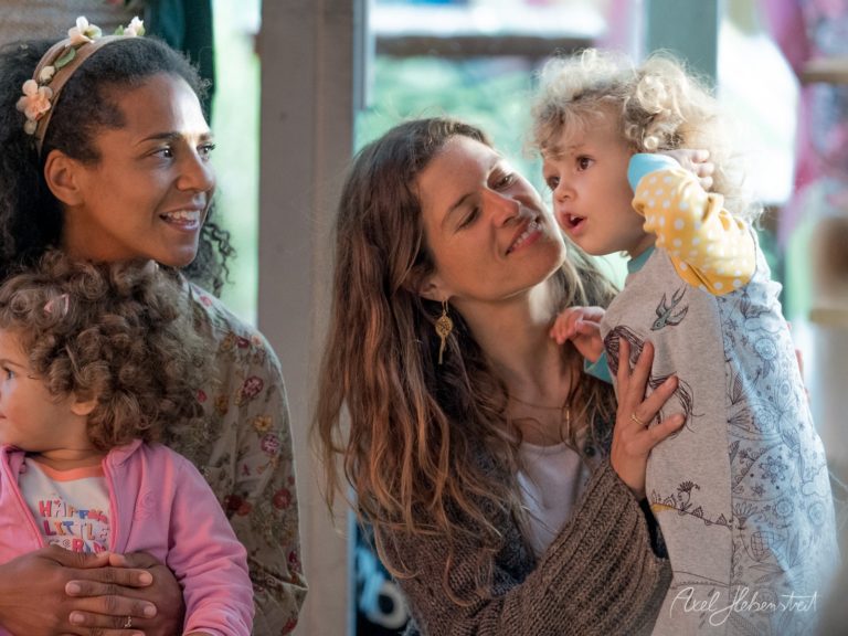 Zwei Frauen mit kleinen Kindern lachen zusammen in einem hellen Innenraum – © Axel Hebenstreit
