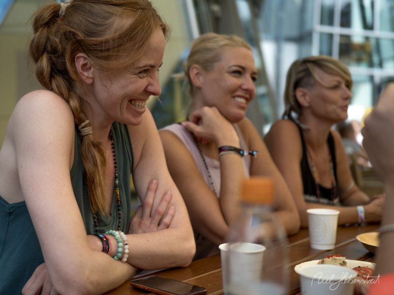 Vier lachende Frauen sitzen zusammen an einem Tisch bei einem gemütlichen Treffen in Innenräumen – © Axel Hebenstreit