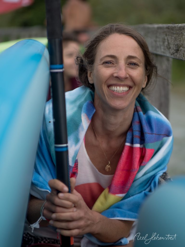 Lächelnde Kajakfahrerin mit Paddel in blauem Kajak beim Wassersport – © Axel Hebenstreit