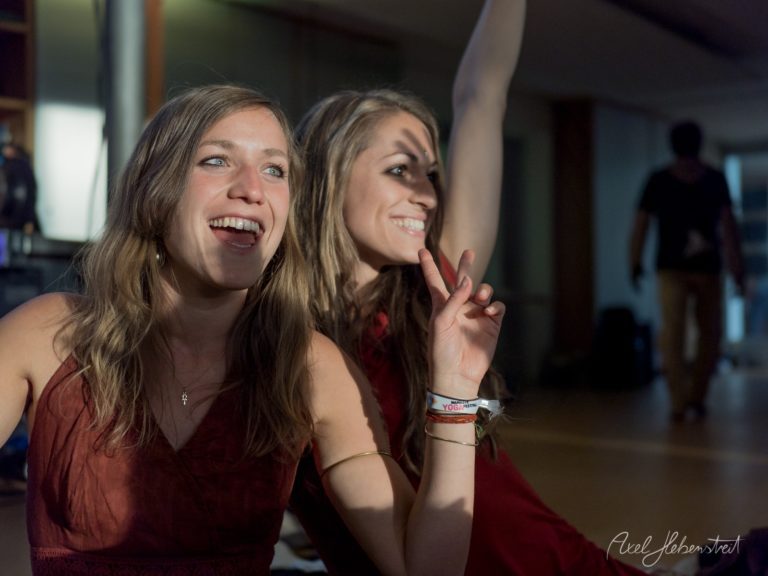 Zwei lachende Frauen in roten Tops genießen ausgelassen ein Festival oder Event in einer Halle – © Axel Hebenstreit