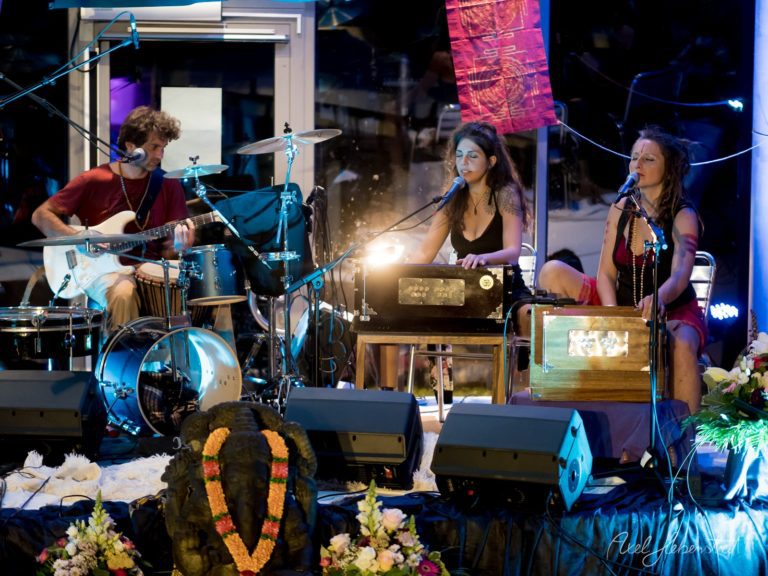 Drei Musikerinnen performen live auf einer beleuchteten Bühne mit Gitarre, Keyboard und Gesang – © Axel Hebenstreit