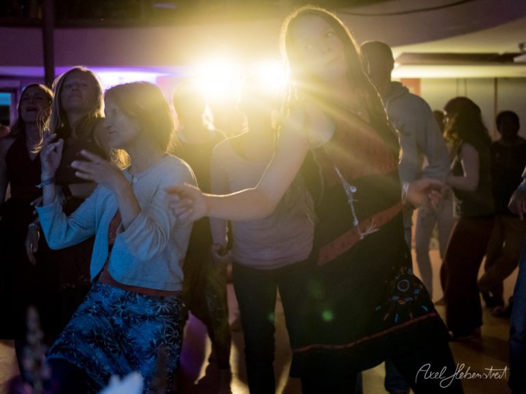 Festivalbesucher tanzen in leuchtender Atmosphäre bei Live-Musik auf einer Indoor-Veranstaltung – © Axel Hebenstreit