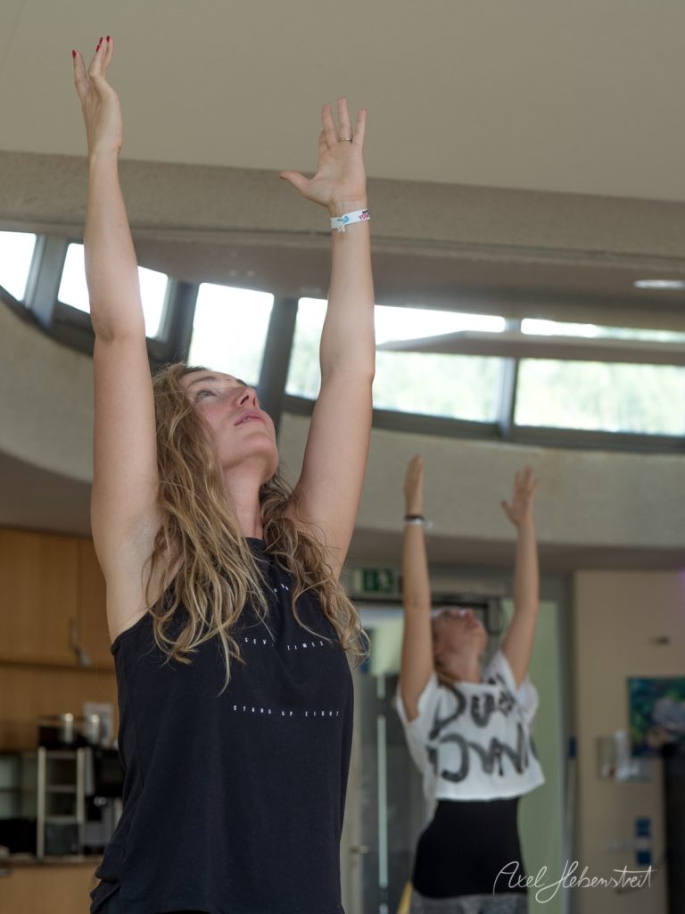 Yogaklasse in heller Turnhalle mit Frauen in Aufwärtshund-Position, konzentrierte Gesichtsausdrücke – © Axel Hebenstreit