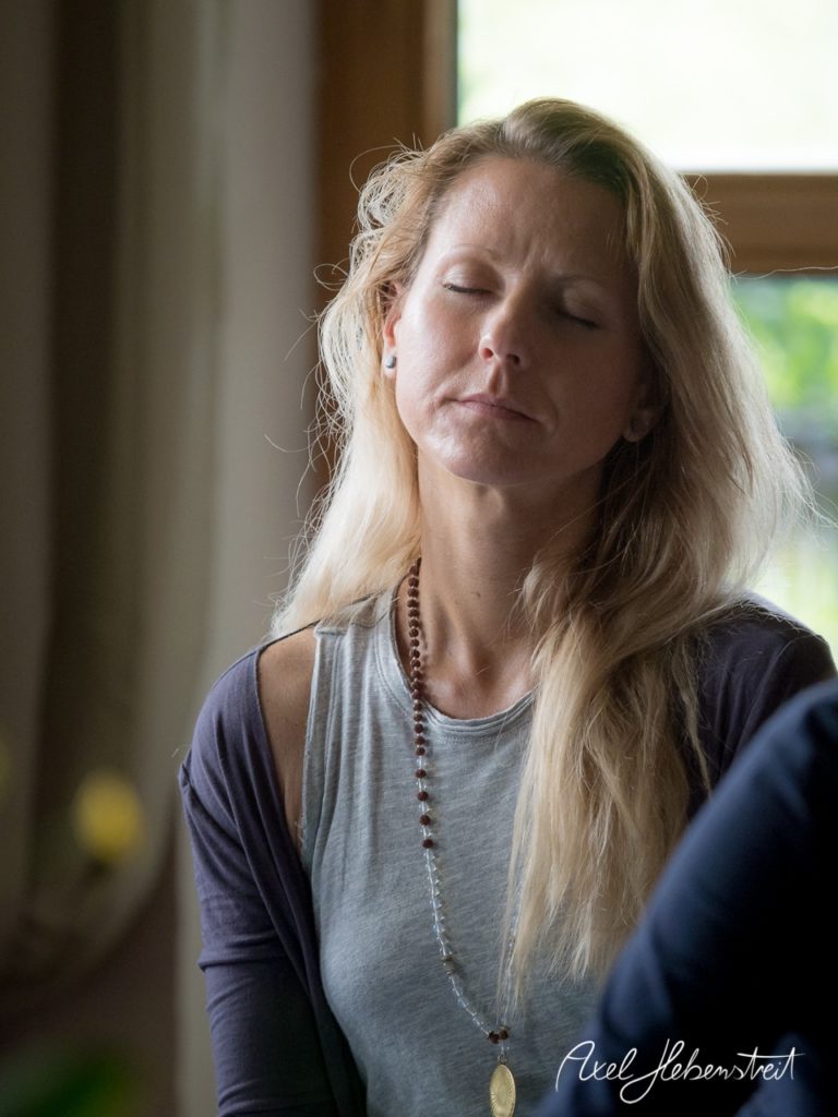 Eine Frau mit langen Haaren meditiert entspannt in einem hellen Raum. – © Axel Hebenstreit
