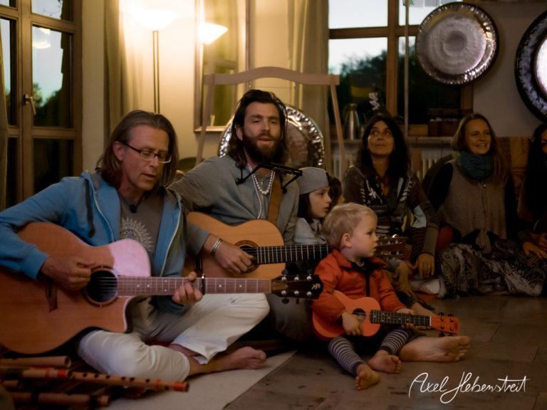 Musikschaffende und Kinder spielen gemeinsam Gitarre in einer entspannten, harmonischen Atmosphäre. – © Axel Hebenstreit