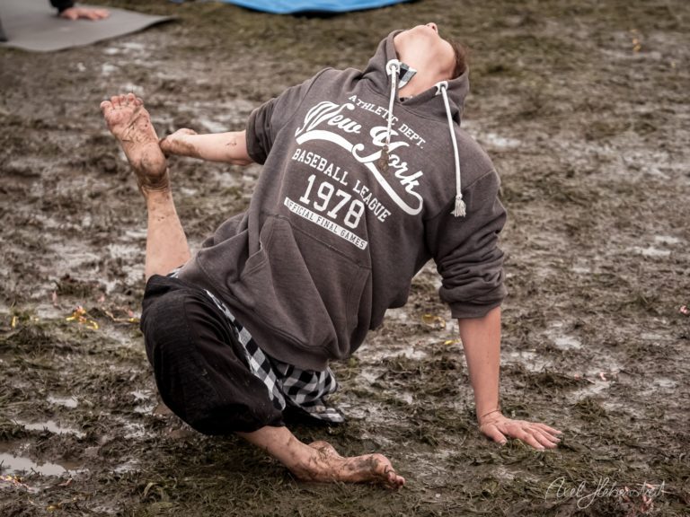 Junger Mann macht Kopfstand im Schlamm auf einem Festival mit Baseball-Hoodie – © Axel Hebenstreit