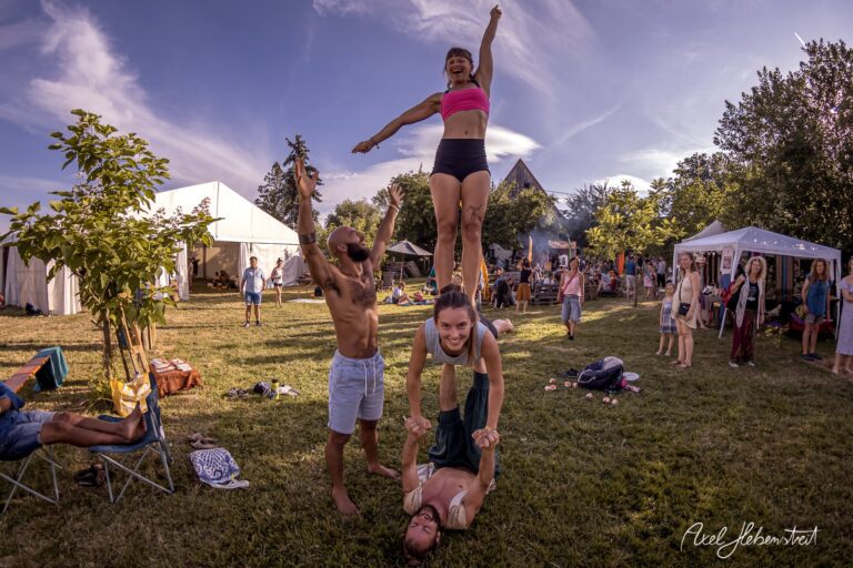 Akrobatische Darbietung einer Gruppe im Festivalkontext auf einer Wiese bei strahlendem Wetter – © Axel Hebenstreit
