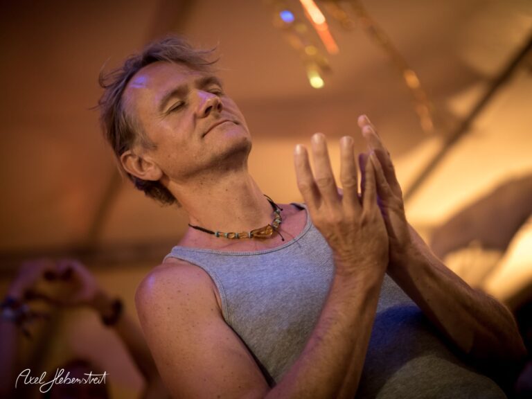 Ein Mann in einem grauen Shirt meditiert mit geschlossenen Augen auf einem Festival – © Axel Hebenstreit