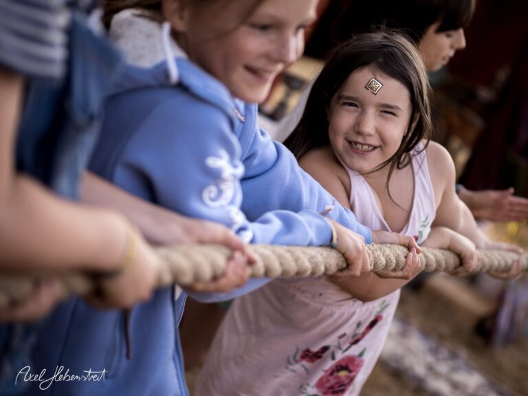 Lächelnde Kinder ziehen gemeinsam an einem Seil und zeigen Teamgeist bei einem Fest in Bayern – © Axel Hebenstreit