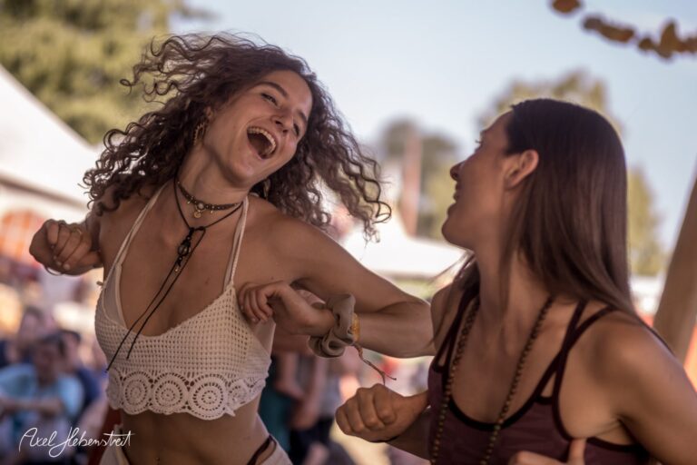 Zwei fröhliche Frauen tanzen ausgelassen auf einem Festival und genießen den Moment – © Axel Hebenstreit.