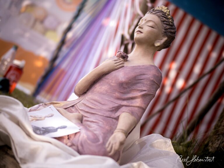 Eine meditative Statue eines Buddhas in einer Festivalumgebung mit sanften Farben und entspannter Atmosphäre – © Axel Hebenstreit.