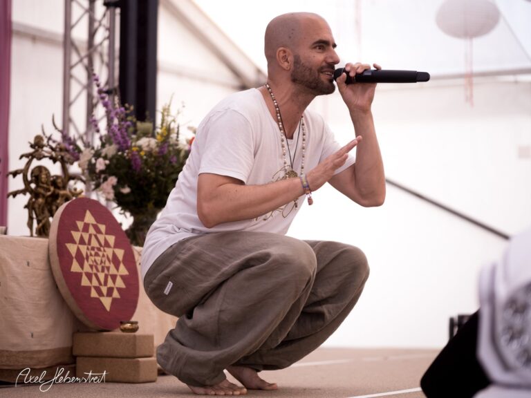 Ein Yoga-Lehrer spricht mit Leidenschaft auf der Bühne während eines Festivals – © Axel Hebenstreit.