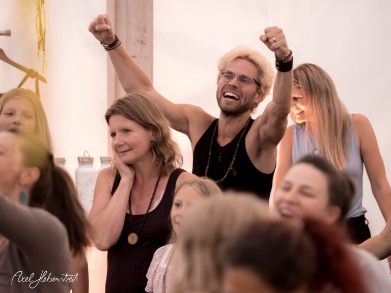Freudvolle Teilnehmer feiern begeistert auf einem Festival in einem Zelt. – © Axel Hebenstreit