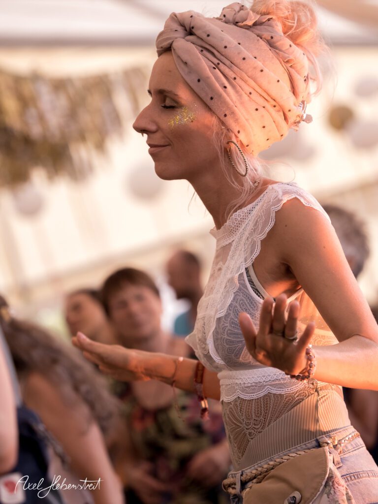 Frau mit Turban tanzt fröhlich auf einem Festival und strahlt Freude und Lebhaftigkeit aus – © Axel Hebenstreit
