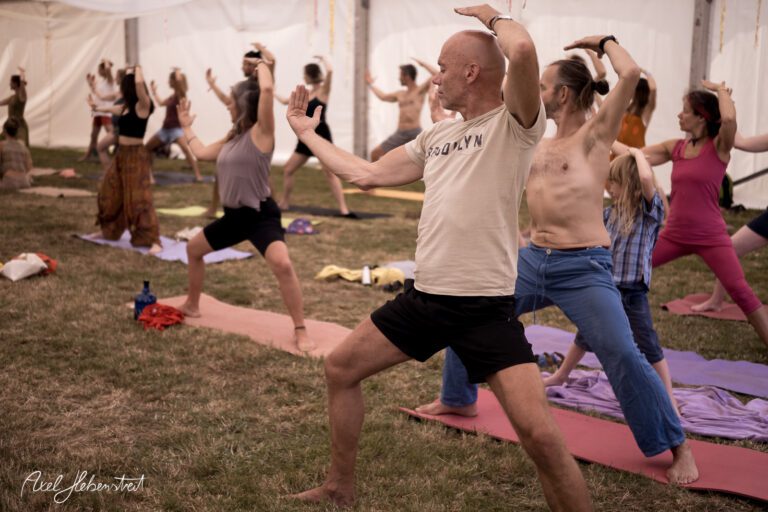 Gruppenyogastunde im Zelt mit Teilnehmern in verschiedenen Positionen auf Matten – © Axel Hebenstreit