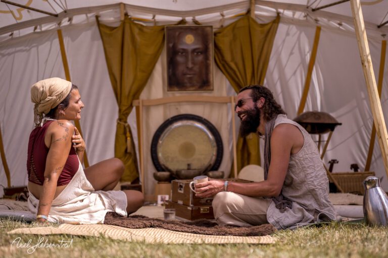Zwei Personen sitzen lächelnd in einem Zelt und teilen einen entspannten Moment in einer Festivalatmosphäre – © Axel Hebenstreit
