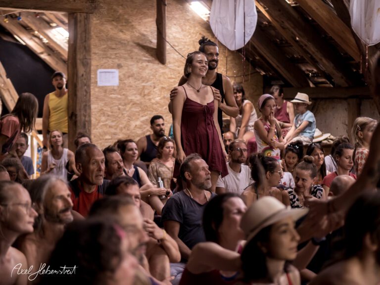 Begeisterte Menschen in einem Festivalraum lauschen einer Präsentation und genießen die Gemeinschaft – © Axel Hebenstreit