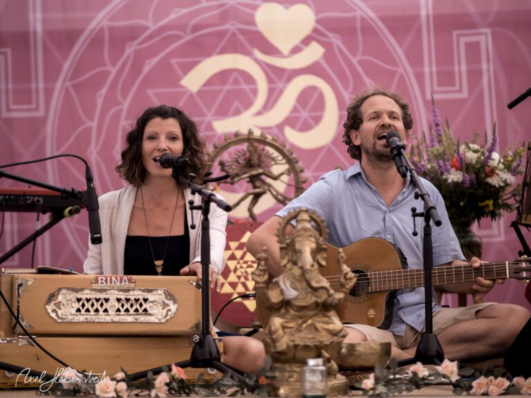 Ein Gesangsduo spielt harmonisch bei einer spirituellen Veranstaltung, umgeben von Blumen und dekorativen Elementen – © Axel Hebenstreit