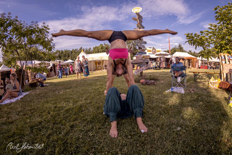 Akrobatische Darbietung auf einem Festival, bei der eine Person auf der Hand einer anderen steht – © Axel Hebenstreit