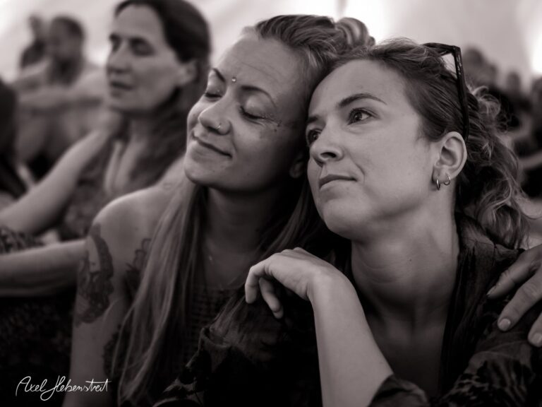 Zwei Frauen sitzen dicht beieinander und genießen einen Moment der Nähe und Verbundenheit bei einem Festival. – © Axel Hebenstreit