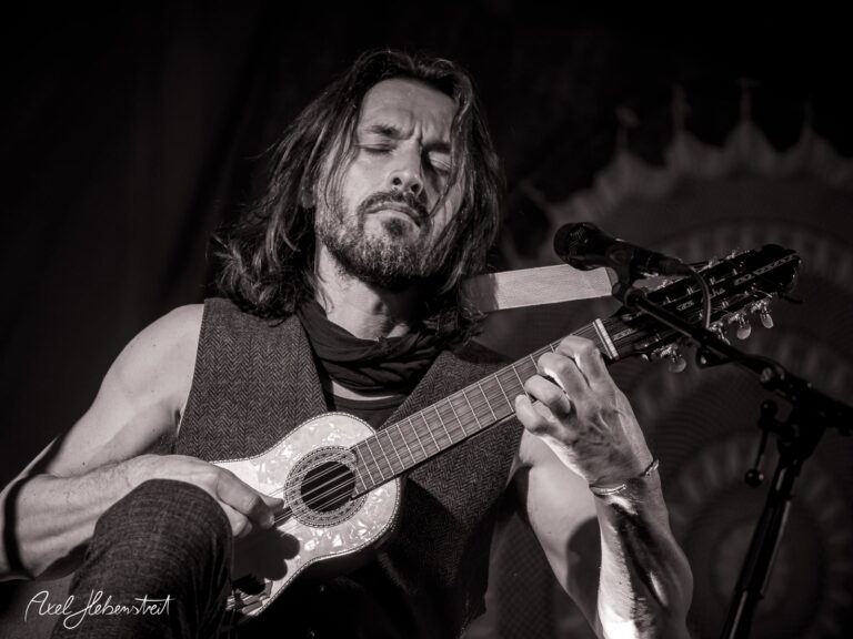 Ein Musiker mit Gitarre spielt intensiv und leidenschaftlich auf der Bühne – © Axel Hebenstreit