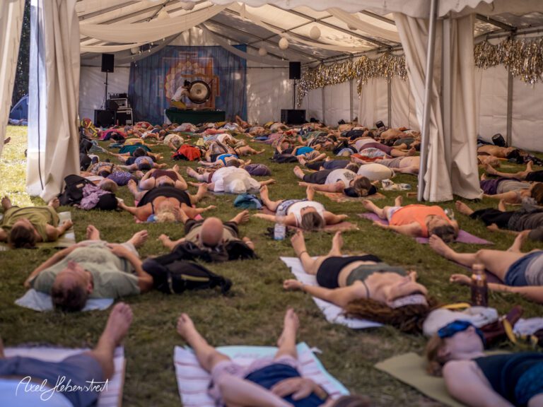 Eine Gruppe von Menschen liegt entspannt im Zelt während einer Yoga- oder Meditationssession – © Axel Hebenstreit