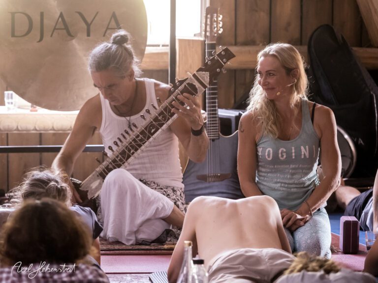 Yoga-Teilnehmer entspannen sich, während ein Musiker ein traditionelles Instrument spielt – © Axel Hebenstreit