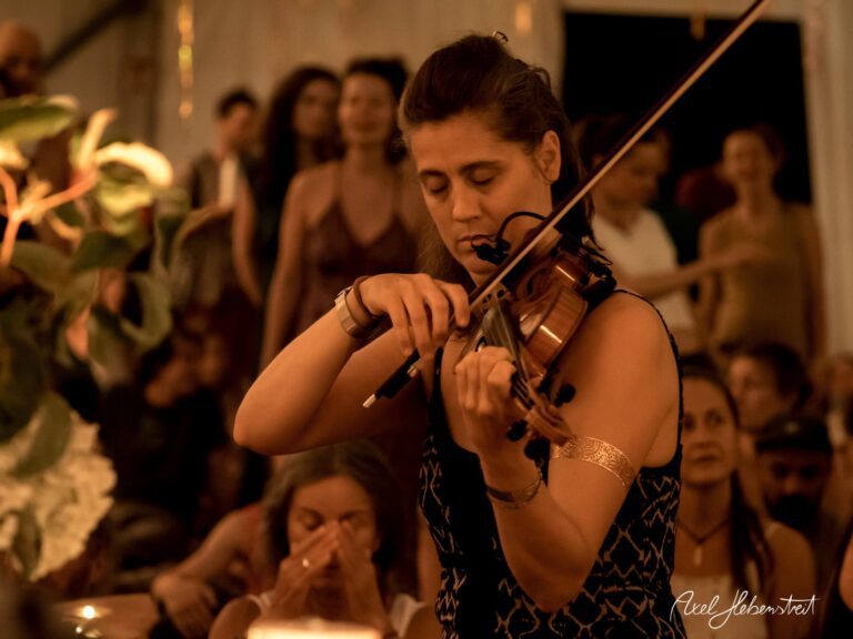 Eine Musikerin spielt intensiv Geige inmitten eines begeisterten Publikums bei einem Festival – © Axel Hebenstreit.