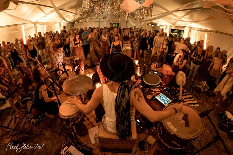 Ein Musiker spielt vor begeistertem Publikum in einem festlich geschmückten Zelt bei einem Festival. – © Axel Hebenstreit