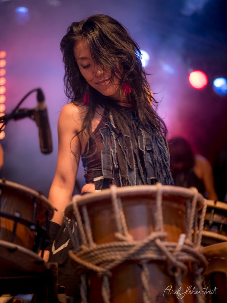Dramatische Szene einer Musikerin, die voller Leidenschaft Percussion auf der Bühne spielt – © Axel Hebenstreit