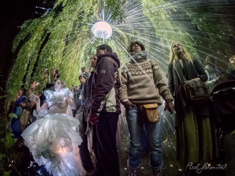 Sammelnde Menschen im Schein von Lichtern unter einem grünen Blätterdach schaffen eine traumhafte, festliche Stimmung – © Axel Hebenstreit