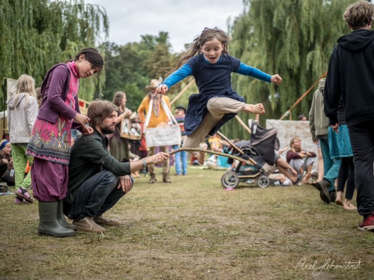 Ein Mädchen springt fröhlich über ein Seil auf einem Festival im Freien – © Axel Hebenstreit