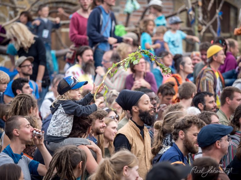 Bunte Festivalatmosphäre mit jubelnden Menschen, ein Kind schwenkt fröhlich einen Zweig – © Axel Hebenstreit