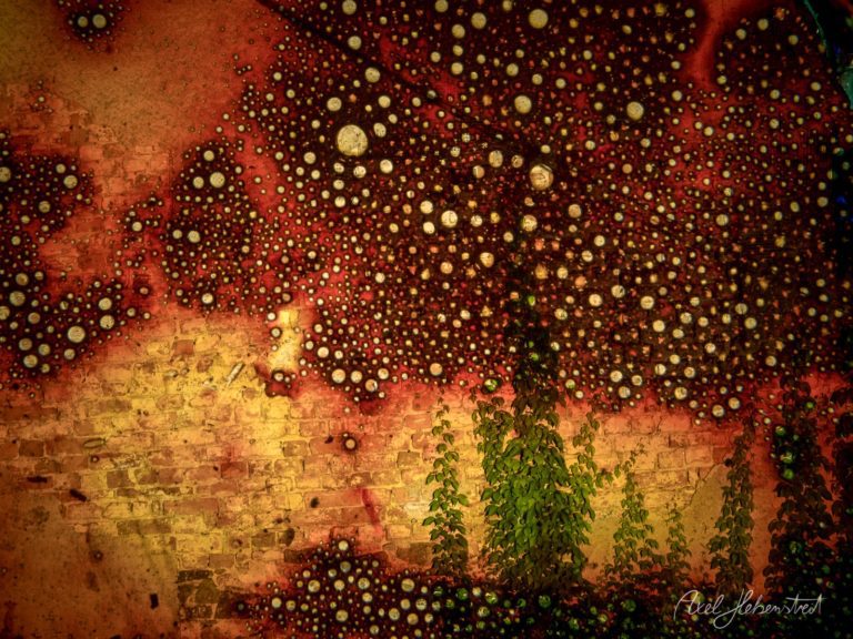 Abstrakte Farben und Lichtpunkte auf einer wandähnlichen Oberfläche, die eine mystische Atmosphäre schaffen – © Axel Hebenstreit