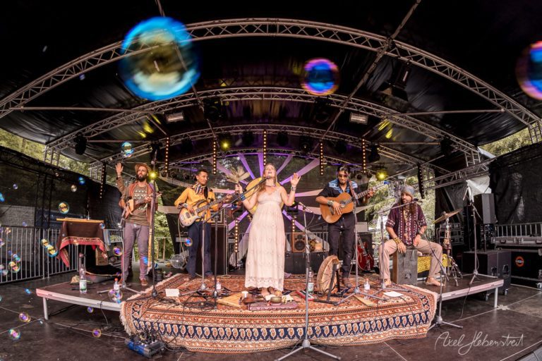 Liveband auf einer Festivalbühne, umgeben von schimmernden Seifenblasen und festlicher Atmosphäre – © Axel Hebenstreit