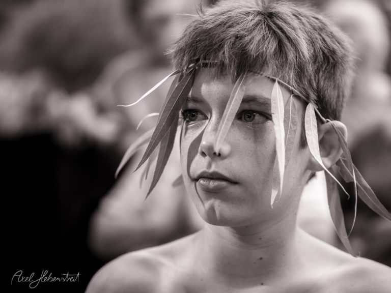 Ein nachdenklicher Junge mit Blättern im Haar in einem feierlichen Anlass, der die Stimmung der Natur und Tradition einfängt – © Axel Hebenstreit