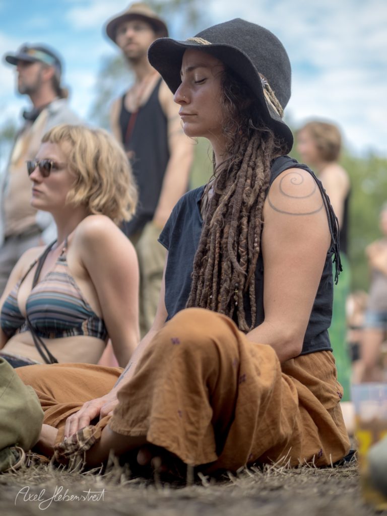 Frau mit Dreads und Hut, meditierend auf einem Festival im Freien – © Axel Hebenstreit