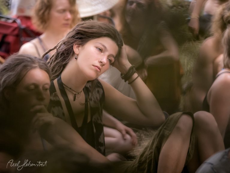 Nachdenkliche junge Frau mit Dreadlocks in einer entspannten Festival-Umgebung – © Axel Hebenstreit