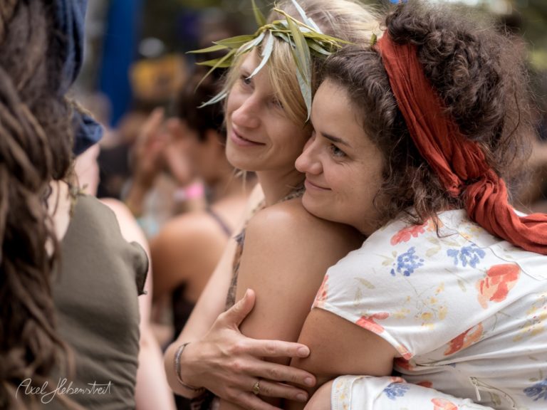 Zwei Frauen umarmen sich herzlich, umgeben von einer festlichen Atmosphäre im Freien – © Axel Hebenstreit.