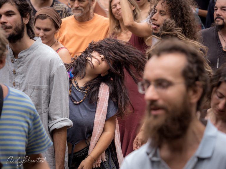 Tanzende Menschenmenge auf einem Festival, mit einer Frau im Mittelpunkt, die ihre Haare im Rhythmus bewegt – © Axel Hebenstreit
