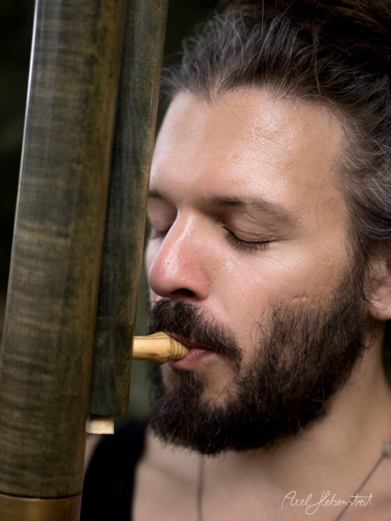 Ein musizierender Mann spielt konzentriert ein Blasinstrument im Freien – © Axel Hebenstreit