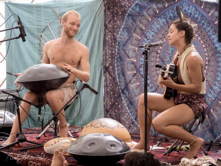 Zwei Musiker in entspannter Atmosphäre spielen Hangpan und Ukulele während eines Konzerts. – © Axel Hebenstreit