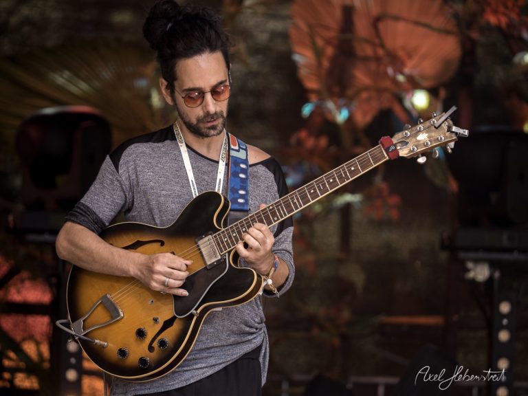 Ein Musiker spielt konzentriert seine Gitarre auf einer Bühne bei einem Festival – © Axel Hebenstreit
