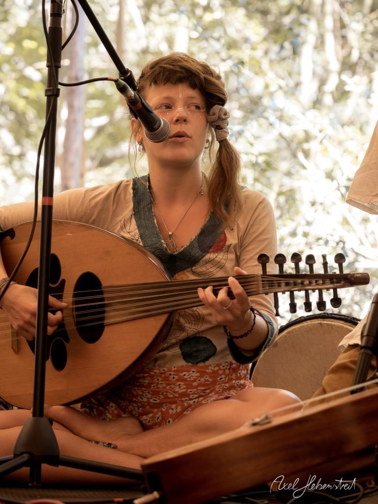 Eine Musikerin spielt auf einem Saiteninstrument während eines Festivals im Freien – © Axel Hebenstreit