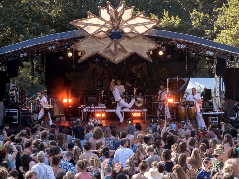 Dynamische Live-Performance auf einer Festivalbühne mit jubelndem Publikum im Hintergrund – © Axel Hebenstreit